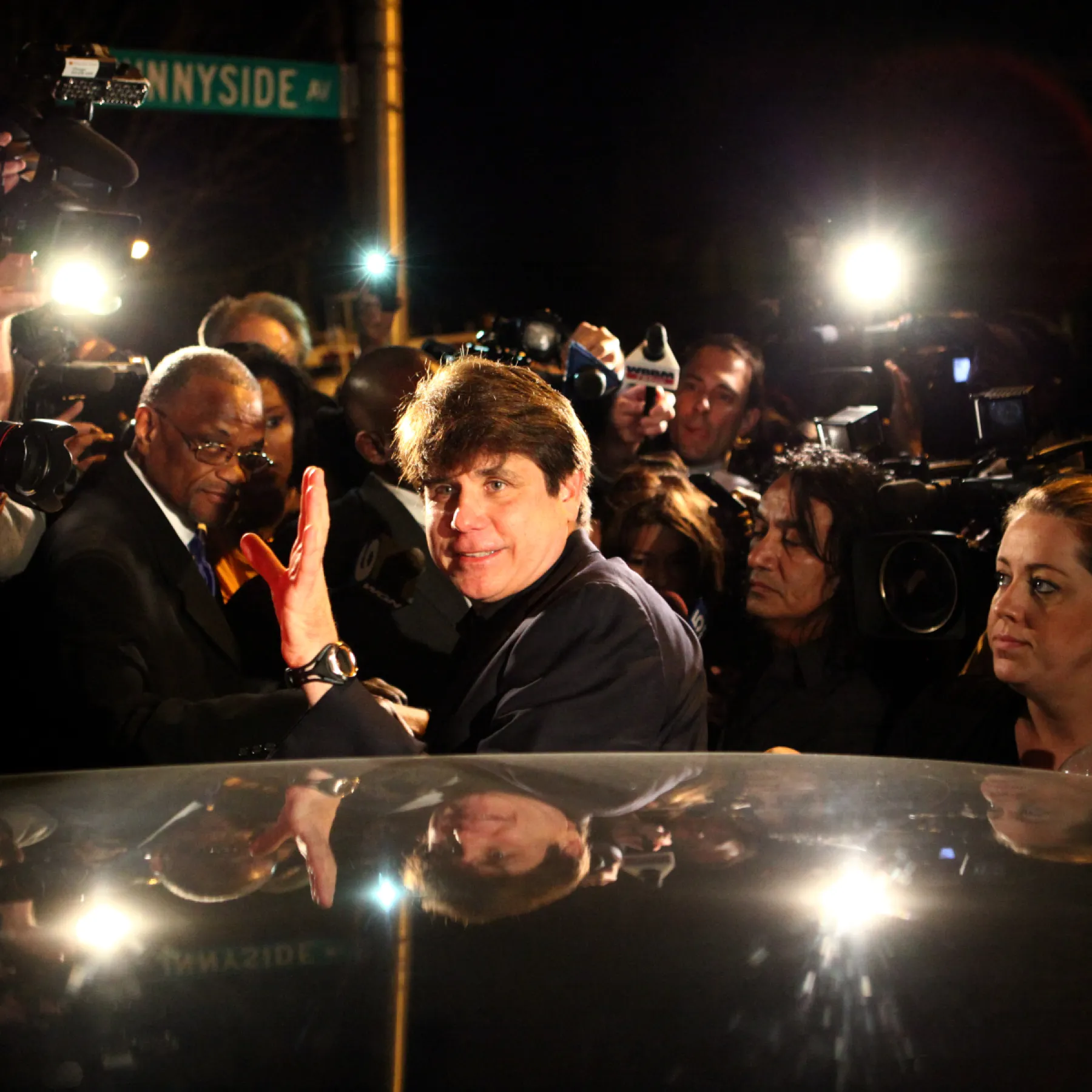 Rod Blagojevich waves to a crowd of reporters and photographers outside his home on Sunnyside Avenue in Chicago's Ravenswood Manor neighborhood