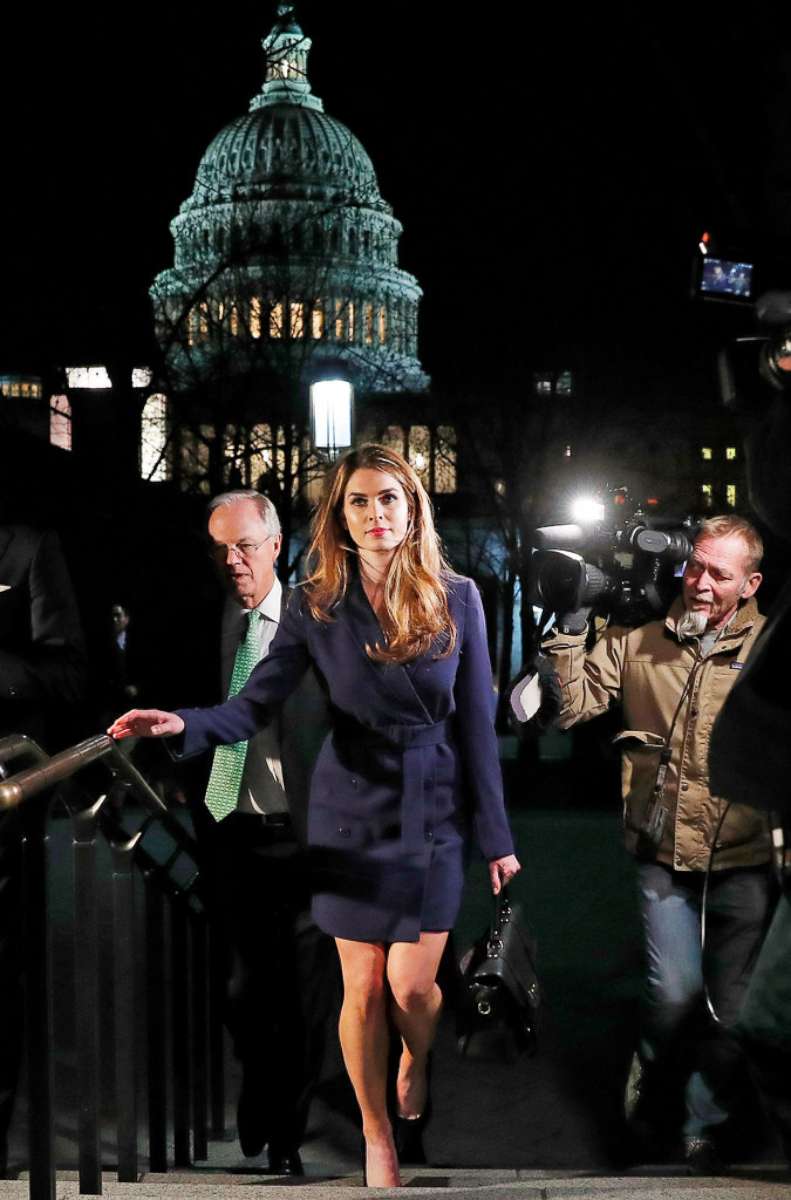 Hope Hicks walking outside the U.S. Capitol at night, surrounded by photographers, with the Capitol dome lit up behind her