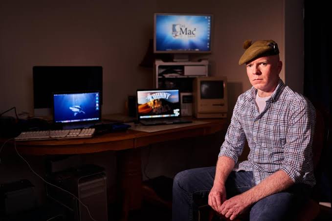 John Paul Mac Isaac, the repair shop owner, sitting among vintage Macintosh computers in his home