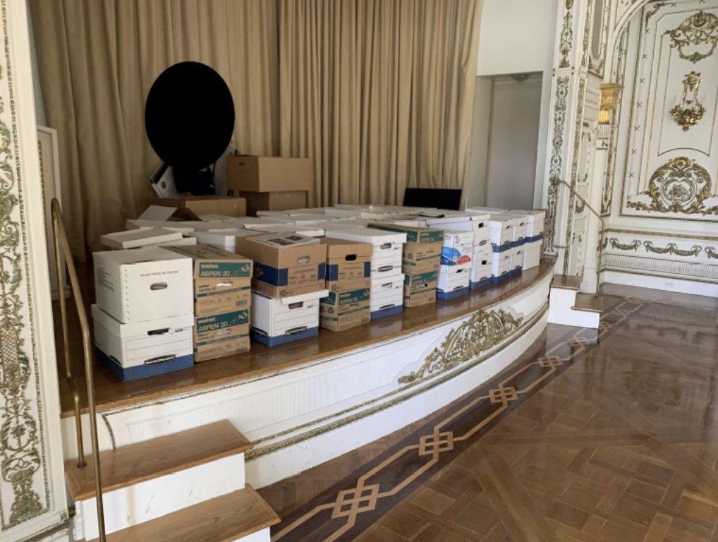 Dozens of banker's boxes stacked on the stage of the White and Gold Ballroom at Mar-a-Lago