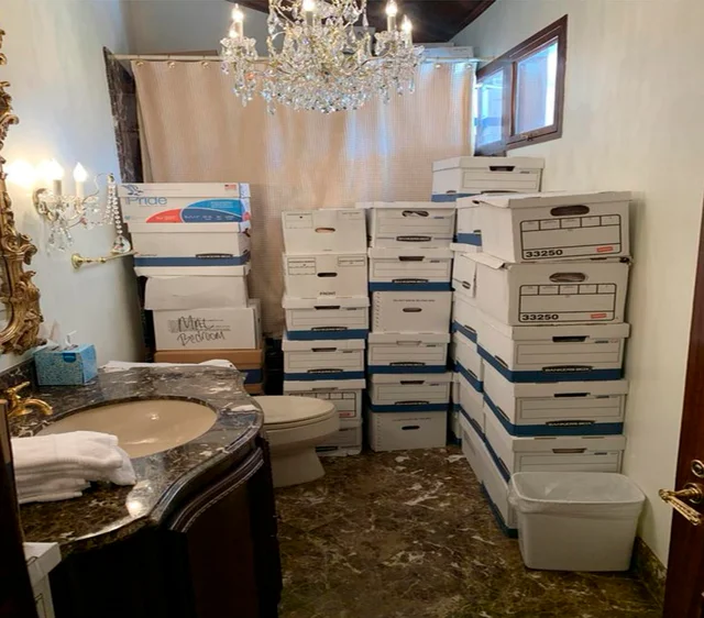 Stacks of banker's boxes filling a Mar-a-Lago bathroom, next to a toilet and under a crystal chandelier