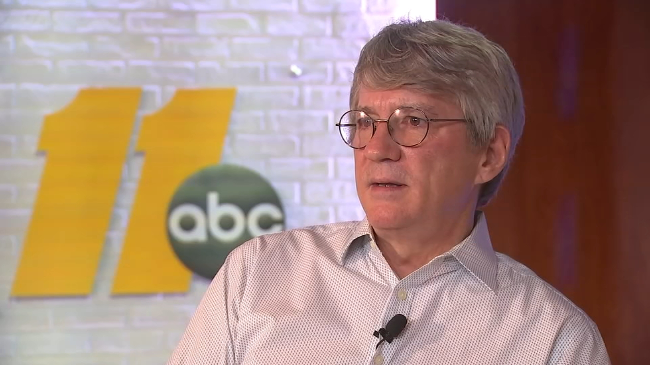 Steve Baker, a gray-haired man in round wire-rimmed glasses and a white patterned button-down shirt with a clip-on microphone, being interviewed in front of a wall with the ABC11 logo