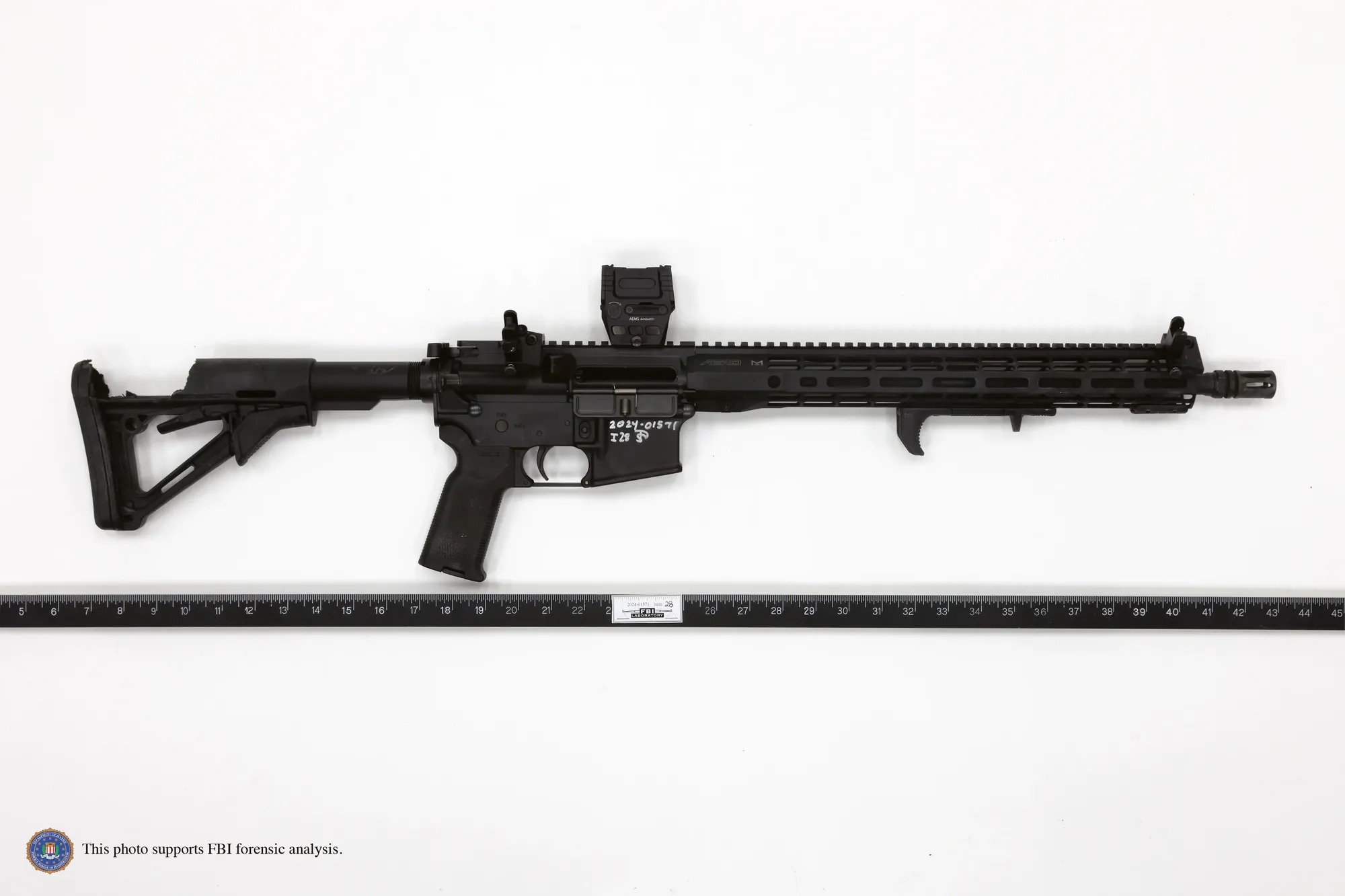 FBI forensic evidence photo of the DPMS Panther Arms AR-15 style rifle recovered from the rooftop, photographed against a white background with an evidence ruler for scale, its stock visibly broken