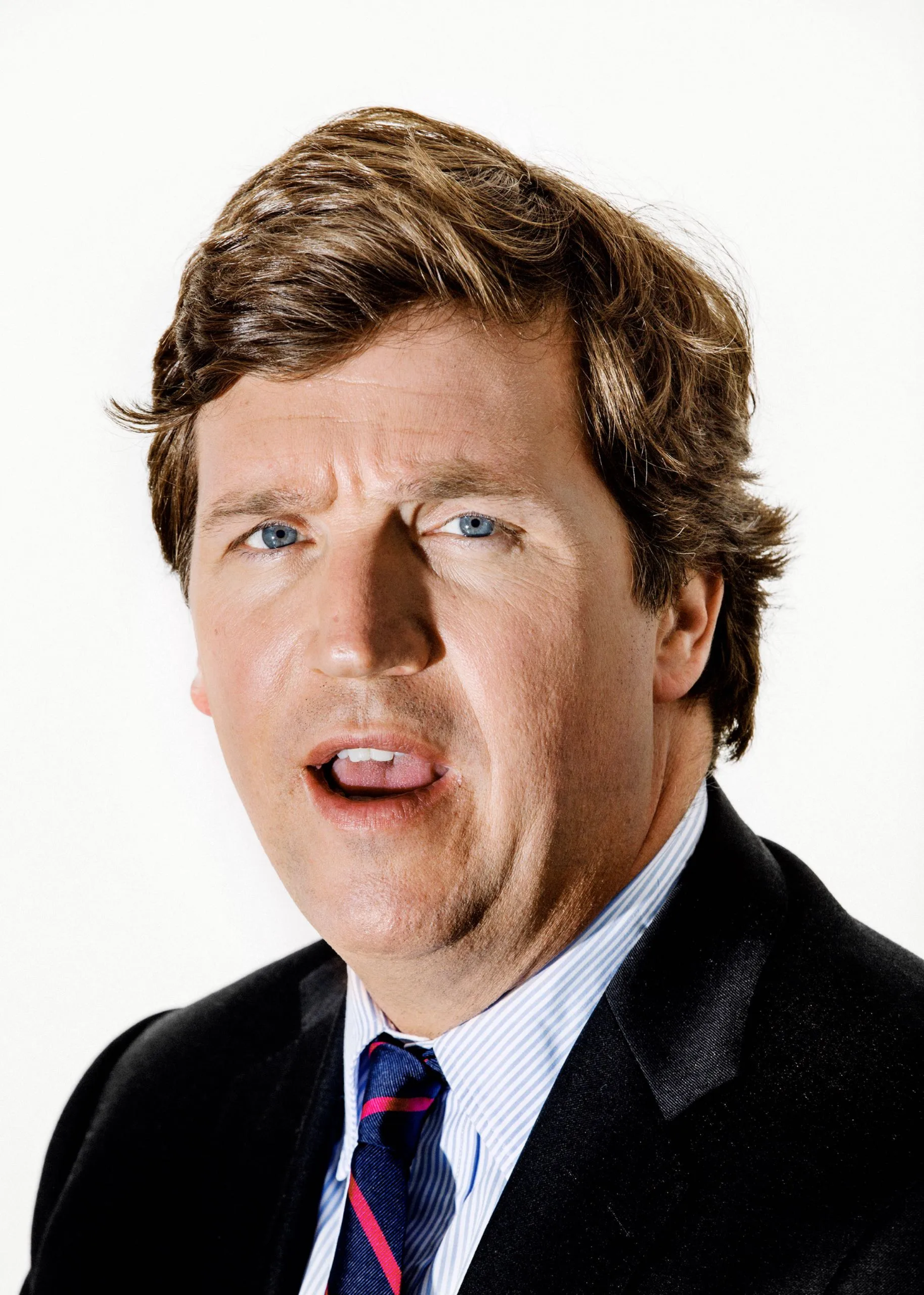 A studio headshot of Tucker Carlson against a plain white background, no network branding in frame